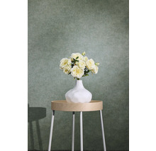 Grön strukturerad non-woven tapet med textiloptik bakom ett sidobord med blomvas.