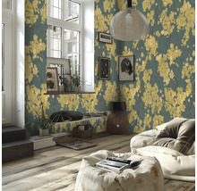 Modernt vardagsrum med non-woven tapet med gula blommotiv på mörk bakgrund, trägolv och ljus saccosäck.