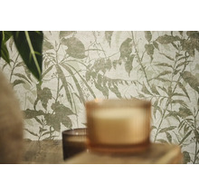 Non-woventapet med botaniskt mönster av blad och grenar i en rumsinteriör med ljus och växter.
