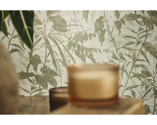 Non-woventapet med botaniskt mönster av blad och grenar i en rumsinteriör med ljus och växter.