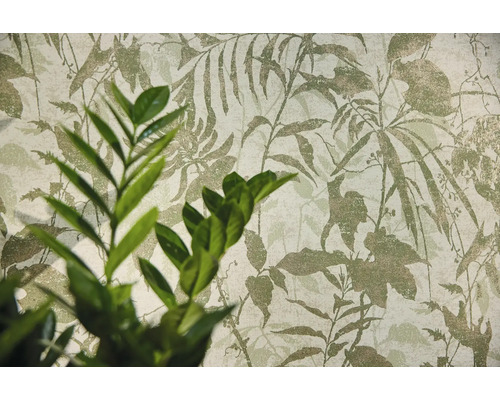 Non-woven tapet med botaniskt bladmotiv och en växt i förgrunden.