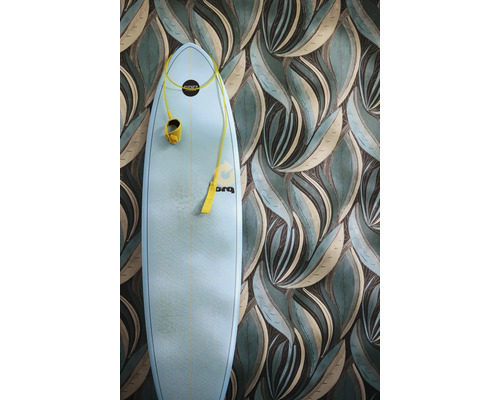 Non-woven tapet med stiliserat bladmönster i grönt och beige, framför står en ljusblå surfbräda.