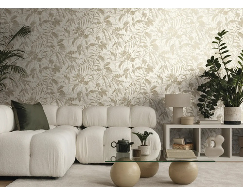 Ljust vardagsrum med non-woven tapet med bladmotiv, vit modulsoffa i bouclétyg och ett soffbord i glas med stenfötter.