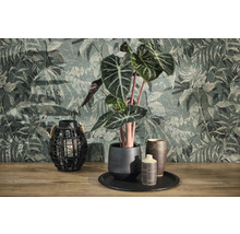Non-woven tapet med djungelmotiv och vintagestruktur bakom en Alocasia-växt i keramikpruka och en gallerlykta på träyta.