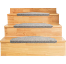 Halvrunda trappstegsmattor av grått textilmaterial på trappsteg av trä.