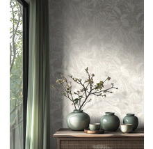 Non-woven tapet med subtilt bladmotiv i ett ljust, naturligt inrett rum med sideboard i trä och keramikvaser.