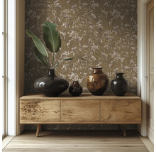 Sideboard i trä framför en vägg med tapet med bladmotiv, dekorerat med olika mörka vaser och stora gröna blad.