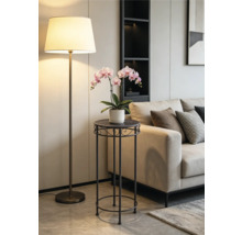 Modernt blombord i metall med en rosa orkidé i ett ljust vardagsrum bredvid en beige soffa och en golvlampa.