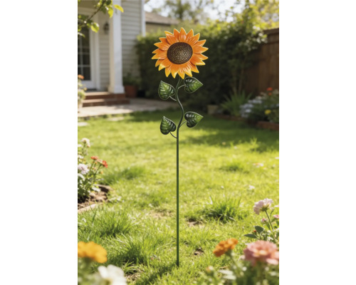 Dekorativ trädgårdspinne i form av en solros av metall på en gräsmatta.