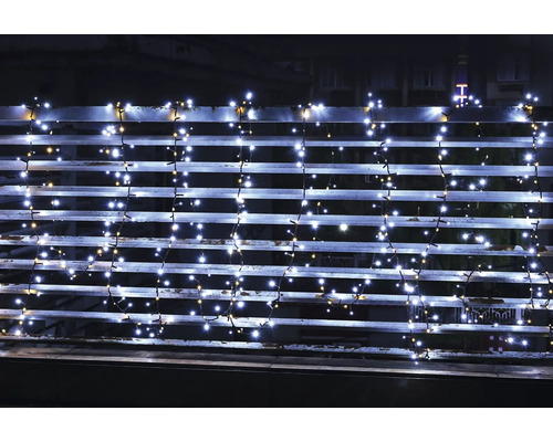LED-ljusslinga med kallvita och varmvita lampor på ett balkongräcke på natten.
