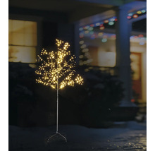 Upplyst LED-dekorationsträd för utomhusbruk med många små ljuspunkter i en trädgård på natten framför ett hus.