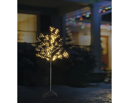 Upplyst LED-dekorationsträd för utomhusbruk med många små ljuspunkter i en trädgård på natten framför ett hus.