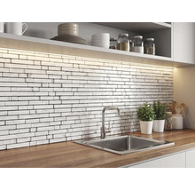 Kök med ett stänkskydd av vit mosaik i tegelstil med marmortextur, bänkskiva i trä, rostfri diskho och LED-belysning.