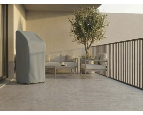 Ljus, modern terrass med ett grått skyddsöverdrag för trädgårdsutrustning, loungemöbler i metall och ett olivträd i kruka.