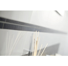 Närbild av vita blanka kakelplattor med en mörk, strukturerad bård.