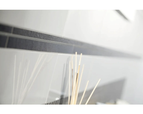 Närbild av vita blanka kakelplattor med en mörk, strukturerad bård.