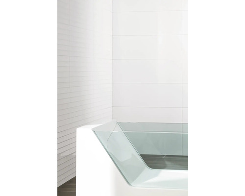 Modernt badkar med sidopanel i glas mot en vitkaklad bakgrund.