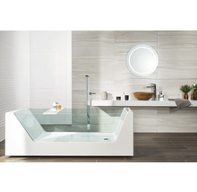 Modernt badrum med badkar i glas, fristående blandare, tvättställ i trä och belyst rund spegel.