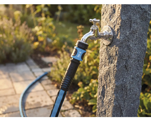 Textilslang med for_q Logo på en utomhuskran på en stenpelare i en trädgård.