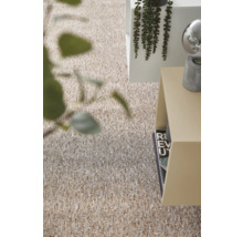 Strukturerad heltäckningsmatta i beige och bruna toner i ett ljust, modernt rum med sidobord och växter.