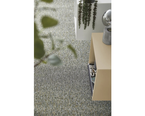 Modern inredning med en texturerad heltäckningsmatta, minimalistiska sidobord och dekorativa gröna växter i ett ljust rum.