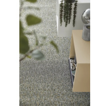 Modern inredning med en texturerad heltäckningsmatta, minimalistiska sidobord och dekorativa gröna växter i ett ljust rum.