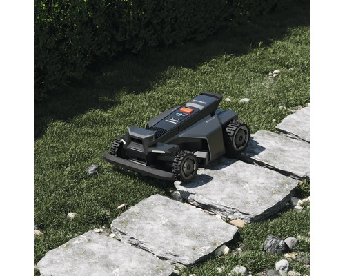 Segway Navimow robotgräsklippare kör över stenplattor i en grönskande trädgård.