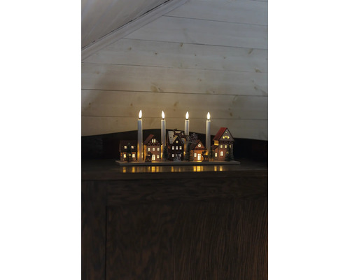 Adventsljusstake i trä med fyra LED-ljus, upplysta miniatyrhus, granar och rensläde.
