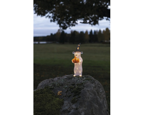 LED akrylfigur mus med häxhatt och pumpa på en mossig sten utomhus.