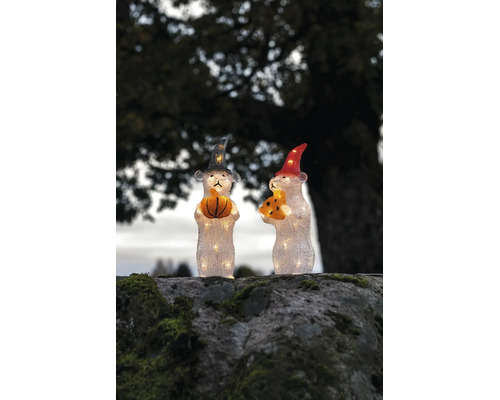 Två belysta LED-musfigurer med hattar, en håller i en pumpa och den andra i en ostbit, på en mossig sten.