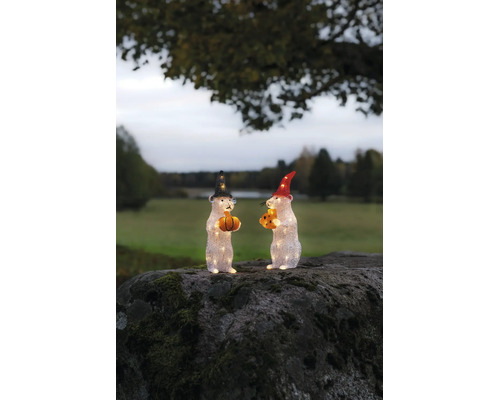 Två belysta musfigurer i akryl med hattar, pumpa och ost på en mossig sten utomhus.