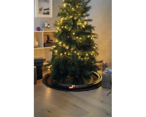 Konstgjord julgran med LED-lampor och ett leksakståg på räls undertill, omgiven av presenter.