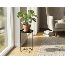 Svart växtställ i metall i ett ljust vardagsrum med en Monstera-växt i en lerkruka.