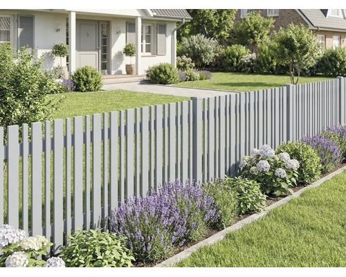 Modernt grått staket i en välskött trädgård med lavendel, hortensior och gräsmatta framför ett hus.