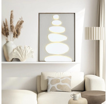 Modern vardagsrum med en minimalistisk tavla med staplade stenar, en beige soffa med en mönstrad kudde och dekorativa tillbehör.