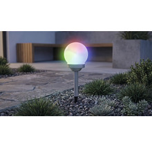 Solcellsdriven globformad trädgårdsbelysning med flerfärgad RGB-belysning, på ett markspett i en grusbädd med växter.