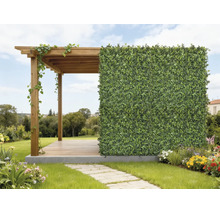 Träpergola med en konstgjord häck som insynsskydd i en ljus, organiserad trädgård med blommor och en stenstig.