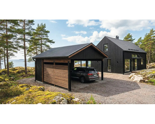 Modern svart carport i trä med korrugerat plåttak bredvid ett matchande hus i ett ljust kustlandskap med havsutsikt.