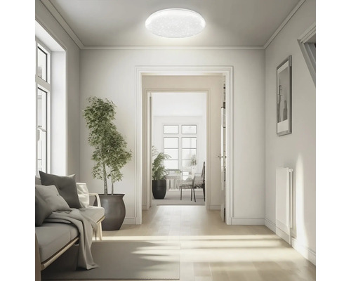 Rund LED-taklampa med stjärneffekt i ett ljust, modernt inrett vardagsrum med utsikt mot hallen.