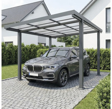 Modern carport i aluminium med ljusgenomsläppligt tak över ett fordon på en stenlagd uppfart bredvid ett hus.