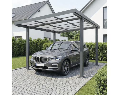 Modern carport i aluminium med ljusgenomsläppligt tak över ett fordon på en stenlagd uppfart bredvid ett hus.
