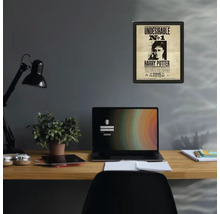 Inramad Harry Potter-poster Undesirable nummer 1 på en grå vägg ovanför ett organiserat skrivbord i trä med bärbar dator och lampa.