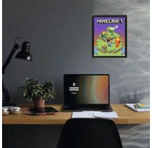 Minecraft-poster i en svart ram på en mörk vägg ovanför ett skrivbord med en bärbar dator och en växt.