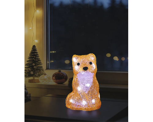 LED-dekorationsfigur räv i akryl med varmvitt ljus i julstämning på ett bord framför ett fönster.