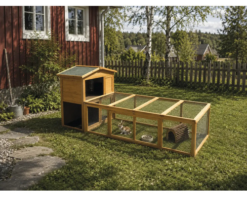 Kaninbur i trä med integrerad utegård och trådnät på en gräsmatta i en trädgård.