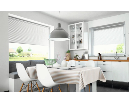 Modern matplats med vit plisségardin, matbord med randig duk och stor grå taklampa.