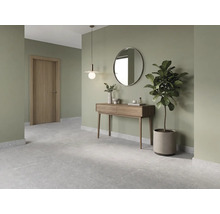 Modern hall med konsolbord av trä, rund spegel, pendellampa, grå golvplattor och salviagröna väggar.