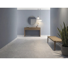 Modern hall med stora golvplattor i stenlook, blå väggar, konsolbord i trä med spegel och en bänk.