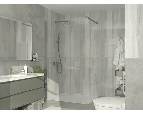 Modern walk-in-dusch med glasvägg, förkromat duschsystem, lågt duschkar och väggkakel i ett ljust badrum.