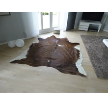 Naturligt formad matta av kohud i ett ljust, modernt inrett vardagsrum med ljust parkettgolv.